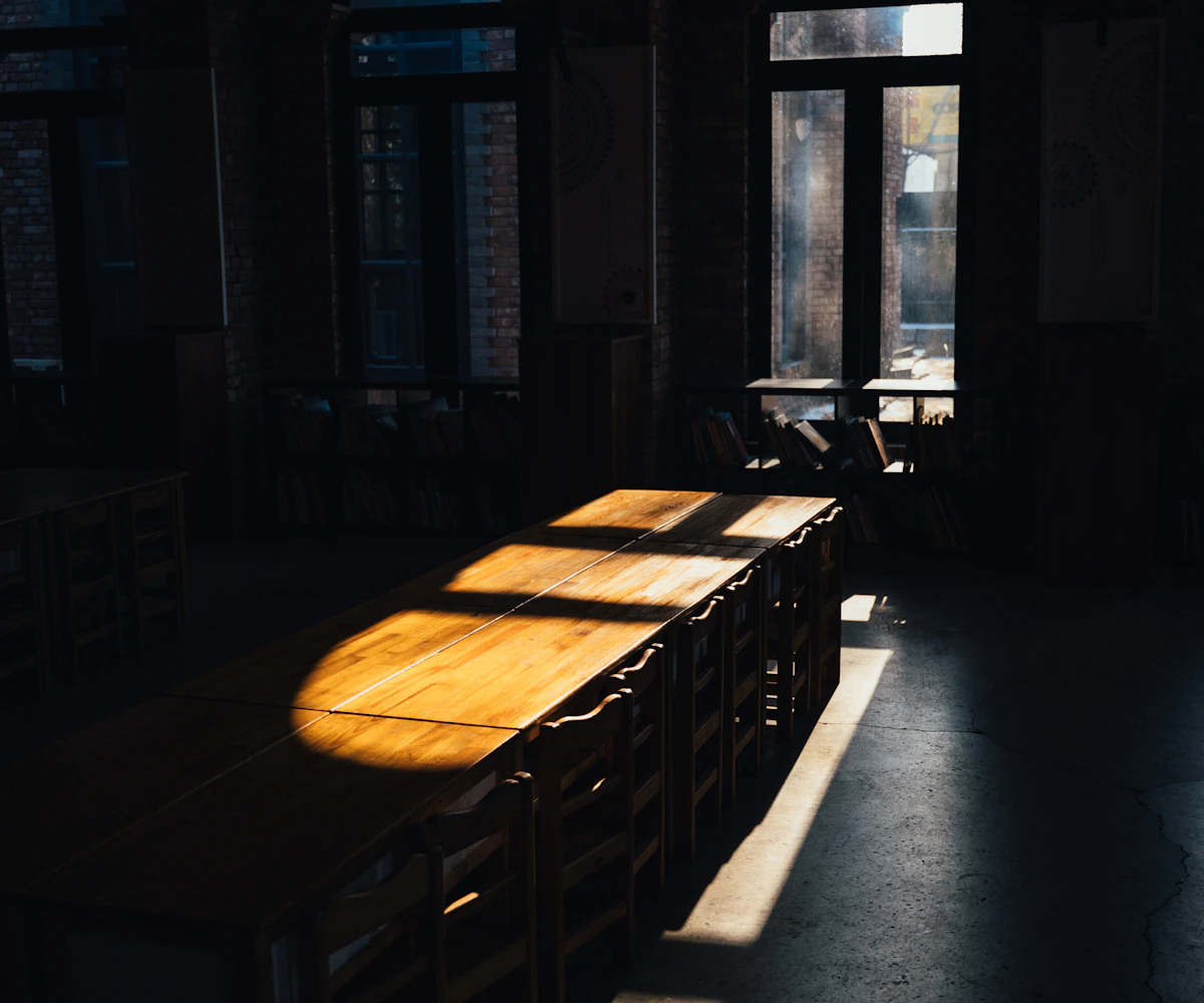 A long empty wooden table in sunlight